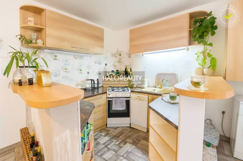 Predaj, rodinný dom Komárno, štvorizbový, čiastočná ... - Kuchyňa v rodinnom dome s rohovou linkou a dreveným dekorom, dekoratívnymi rastlinami na poličkách.