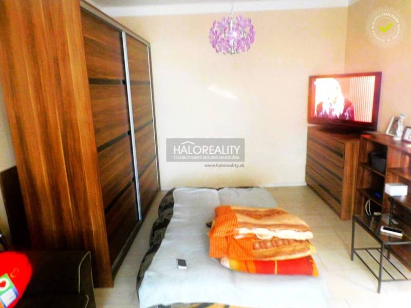 Predaj, dvojizbový byt Topoľčany, Centrum - Spálňa v 2-izbovom byte s posteľou, sedačkou a skrinkou s dreveným dekorom.