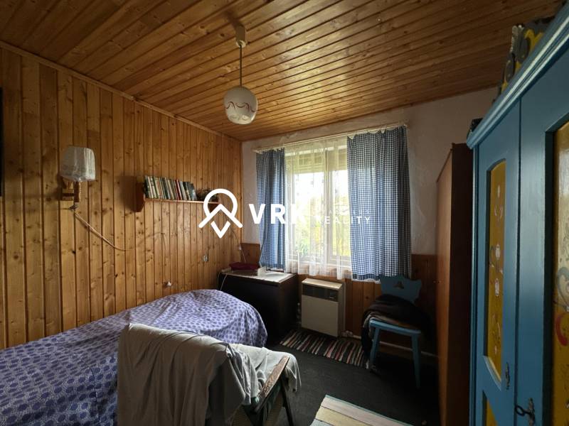 RODINNÝ DOM - CHALUPA, KALŠA - Izba v rodinnom dome s drevom obloženými stenami, modrou skriňou a posteľou.