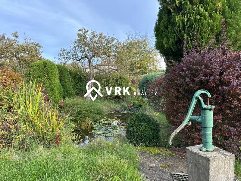 RODINNÝ DOM - CHALUPA, KALŠA - Záhrada rodinného domu v Kalši so starou pumpou a veľkým množstvom zelene.