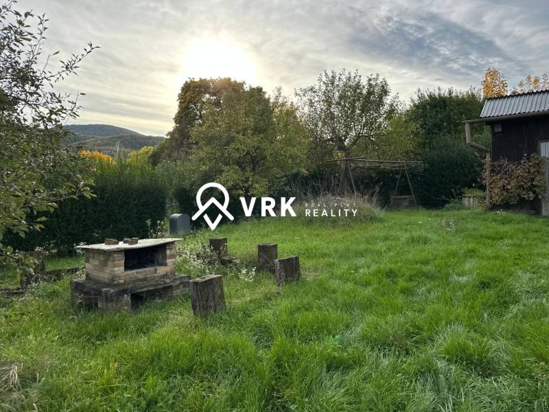 RODINNÝ DOM - CHALUPA, KALŠA - Záhrada rodinného domu v Kalši s krbom a zeleňou na pozadí.