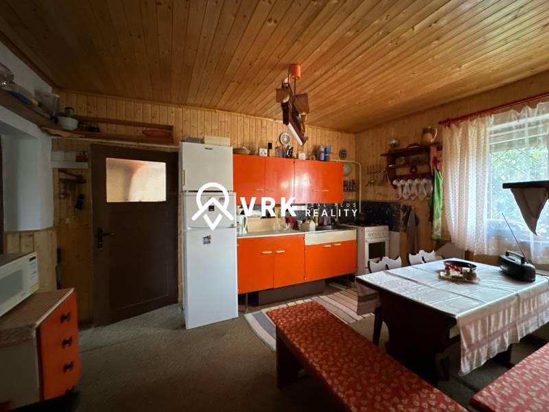 RODINNÝ DOM - CHALUPA, KALŠA - Kuchyňa v rodinnom dome so starožitným nábytkom, rustikálna stena, veľké okno.