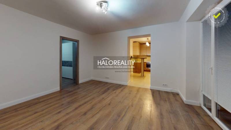 REZERVOVANÉ - Predaj, dvojizbový byt Spišská Nová Ve... - Obývacia izba v 2-izbovom byte s podlahou s dreveným dekorom a vstupom do kuchyne.