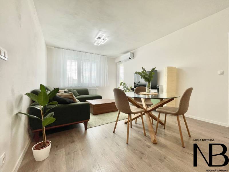 Na predaj štýlový 2-izbový byt s loggiou a parkovaním – TN, Na Pažiti - Svetlá obývacia izba v 2-izbovom byte s podlahou s dreveným dekorom a zelenou pohovkou.