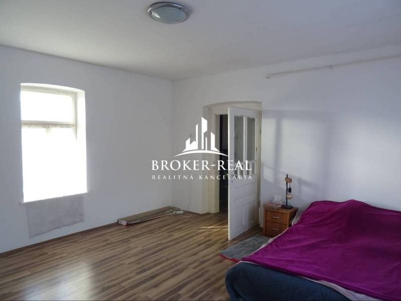 Rodinný dom Rudabanya, Maďarsko - Izba s posteľou, oknom, podlahou s dreveným dekorom, nočným stolíkom a otvorenými dverami.