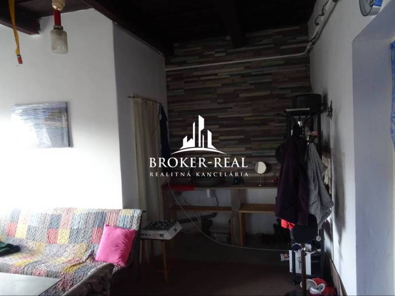 Rodinný dom Rudabanya, Maďarsko - Interiér rodinného domu so sedačkou a vešiakom, obložená stena v pozadí.