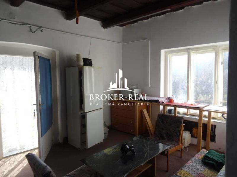 Rodinný dom Rudabanya, Maďarsko - Izba v rodinnom dome s presvetleným stolom pri okne, kreslom a jedálenským stolom.