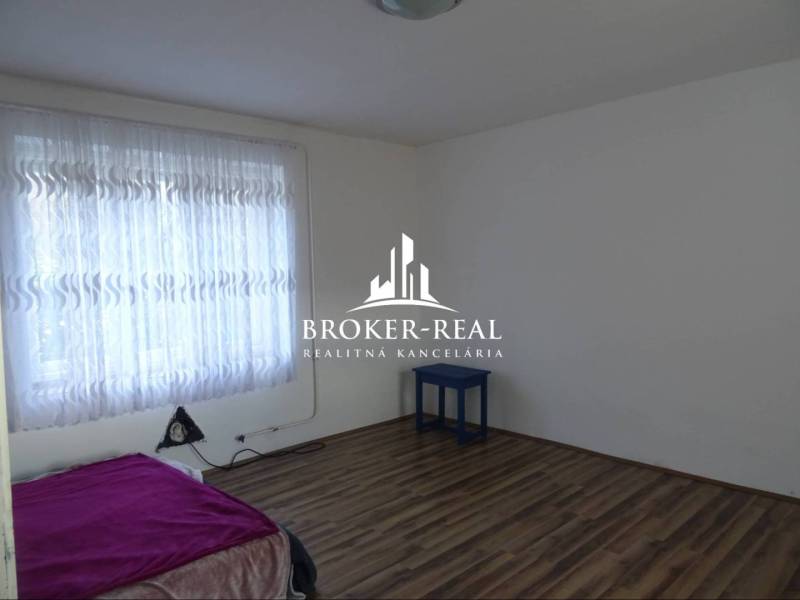 Rodinný dom Rudabanya, Maďarsko - Izba s posteľou, záclonami a podlahou s dreveným dekorom v rodinnom dome.