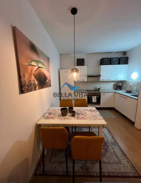 PRENÁJOM - Moderný 2 izbový byt, Galanta-GALA Residence - Kuchyňa 2-izbového bytu s jedálenským stolom, žltými stoličkami a podlahou s dreveným dekorom.