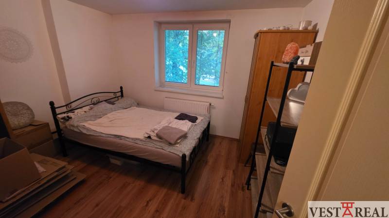 Na prenájom 3 izbový byt z balkónom a parkovacím miestom - Spálňa v 3-izbovom byte s kovovou posteľou a podlahou s dreveným dekorom.