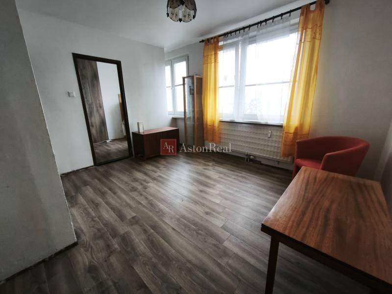 PREDAJ: 1i byt 30m2 - BAURING - FONČORDA - Orenburská ul. - Obývacia izba v 1-izbovom byte s podlahou s dreveným dekorom a žltými závesmi.