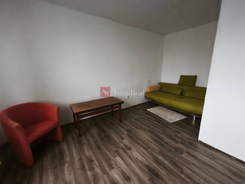 PREDAJ: 1i byt 30m2 - BAURING - FONČORDA - Orenburská ul. - 1-izbový byt s podlahou s dreveným dekorom, zelenou pohovkou a červeným kreslom.