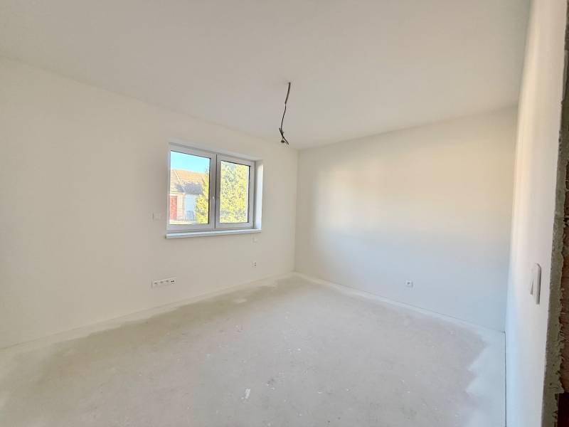 NOVOSTAVBA  ATRAKTÍVNY 4 I RODINNÝ DOM,650m2 pozemok - Priestranná, svetlá izba v rodinnom dome s dvojitým oknom a bielymi stenami.