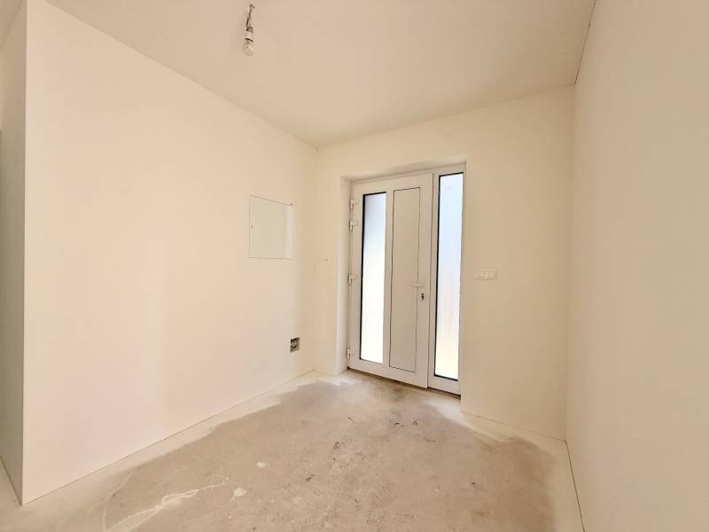 NOVOSTAVBA  ATRAKTÍVNY 4 I RODINNÝ DOM,650m2 pozemok - Prázdna miestnosť s francúzskymi dverami v rodinnom dome, biele steny, betónová podlaha.