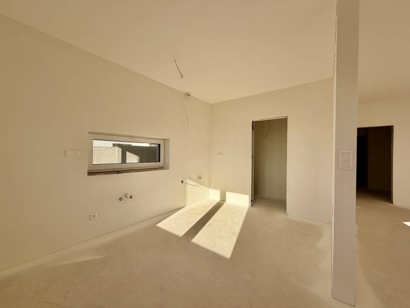 NOVOSTAVBA  ATRAKTÍVNY 4 I RODINNÝ DOM,650m2 pozemok - Priestranná nevybavená miestnosť v rodinnom dome s oknom a dverami bez podlahy.