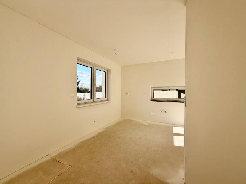 NOVOSTAVBA  ATRAKTÍVNY 4 I RODINNÝ DOM,650m2 pozemok - Prázdna izba s dvojitým oknom a betónovou podlahou v rodinnom dome.