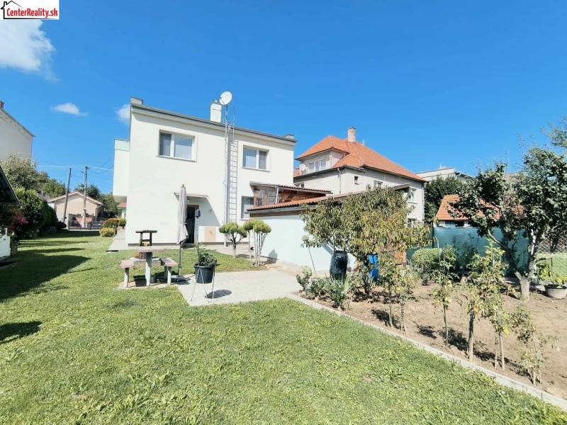 ‼️RODINNÝ DOM S KRÁSNYM POZEMKOM NA PREDAJ,KOLAČNO okr. PARTIZÁNSKE ‼️ - Rodinný dom v Partizánskom obklopený zeleným trávnikom a záhradou pod modrou oblohou.