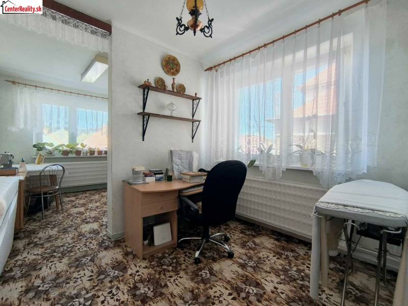 ‼️RODINNÝ DOM S KRÁSNYM POZEMKOM NA PREDAJ,KOLAČNO okr. PARTIZÁNSKE ‼️ - Izba v rodinnom dome s písacím stolom, rastlinami a kobercom s kvetinovým vzorom.