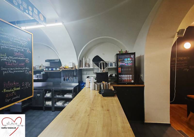 Odstúpenie prenájmu zabehnutej street food reštaurácie – centrum Trnav - Interiér gastro priestoru s podlahou s dreveným dekorom, pracovnou doskou a nápojovým chladením.