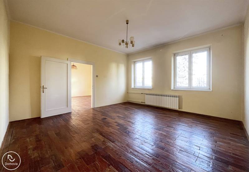 Exkluzívne | Na predaj 5i byt s garážou a záhradou v centre Ružomberka - Priestranná izba s podlahou s dreveným dekorom a dvomi veľkými oknami.