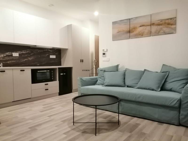 ŠIKOVNÁ GARSÓNKA na PRENÁJOM v CENTRE MESTA na BEZRUČOVEJ ul. - Garsónka s kuchyňou, modrým gaučom, okrúhlym stolíkom a podlahou s dreveným dekorom.