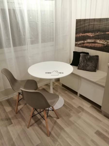 ŠIKOVNÁ GARSÓNKA na PRENÁJOM v CENTRE MESTA na BEZRUČOVEJ ul. - Jedálenský kút s okrúhlym stolom, dvomi stoličkami a dekoračnými vankúšmi, podlaha s dreveným dekorom.