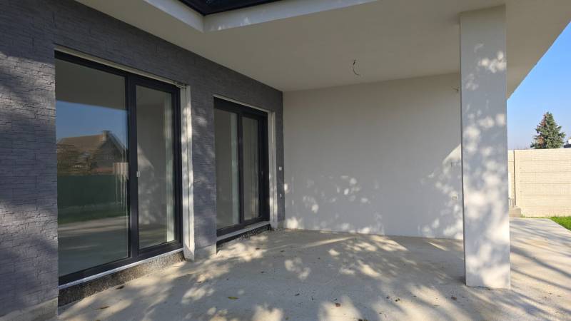 4 izbový BUNGALOV novostavba (VYSTAVBA) Piešťany, kvalitné prevedenie - Terasa rodinného domu v Piešťanoch s veľkými oknami a kamenným dekorom.