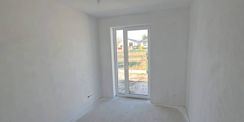 4 izbový BUNGALOV novostavba (VYSTAVBA) Piešťany, kvalitné prevedenie - Biela miestnosť v rodinnom dome s veľkým oknom a výhľadom na záhradu.