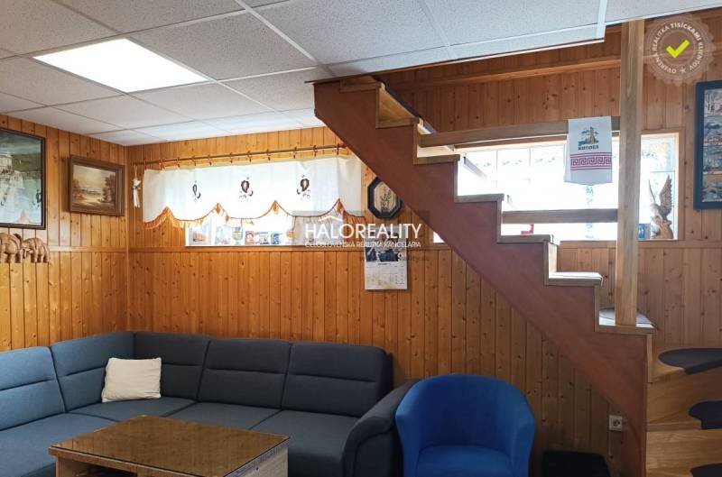 Predaj, chata Byšta - EXKLUZÍVNE HALO REALITY - Interiér chaty s dreveným obkladom, schodmi, sedačkou a dekoráciami na stenách.