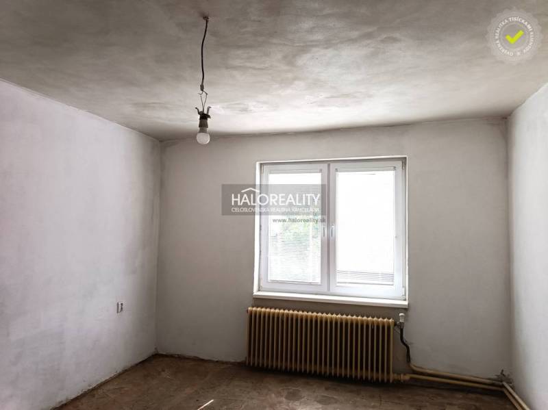 Predaj, rodinný dom Zemplín - EXKLUZÍVNE HALO REALITY - Prázdna miestnosť v rodinnom dome s bielymi stenami, radiátorom a oknom.