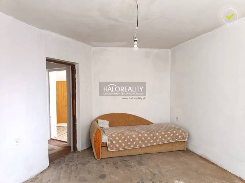 Predaj, rodinný dom Zemplín - EXKLUZÍVNE HALO REALITY - Interiér rodinného domu so starším gaučom a surovou betónovou podlahou.