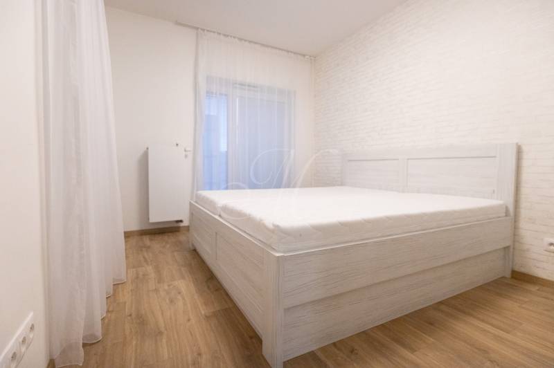 Zariadený 2i byt s lodžiou v rezidencii Pri Mýte - Spálňa v 2-izbovom byte s posteľou a podlahou s dreveným dekorom.