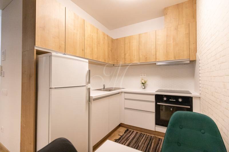 Zariadený 2i byt s lodžiou v rezidencii Pri Mýte - Kuchyňa v 2-izbovom byte s dreveným dekorom a bielymi skrinkami.