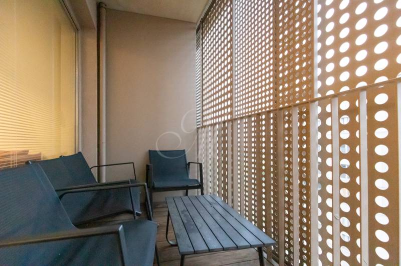 Zariadený 2i byt s lodžiou v rezidencii Pri Mýte - Balkón s dreveným dekorom, posedením a perforovanou stenou v 2-izbovom byte.