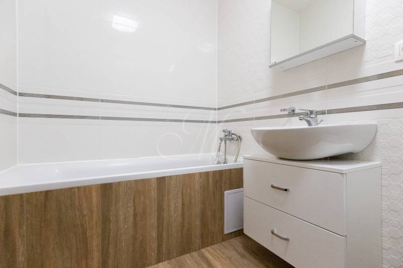 Zariadený 2i byt s lodžiou v rezidencii Pri Mýte - Kúpeľňa v 2-izbovom byte s vaňou, umývadlom a podlahou s dreveným dekorom.