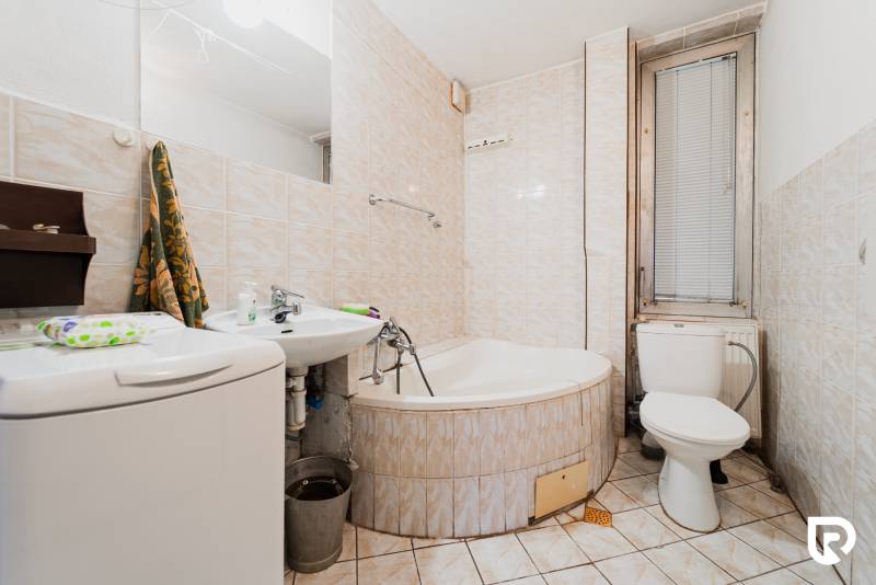 Pozemky s dvoma domami na prestavbu alebo novostavbu - Kúpeľňa s vaňou, umývadlom a práčkou v rodinnom dome.