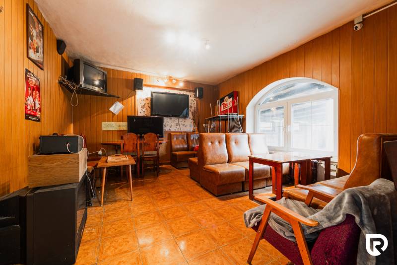 Pozemky s dvoma domami na prestavbu alebo novostavbu - Interiér rodinného domu s koženými sedačkami, dreveným obkladom a televízormi.