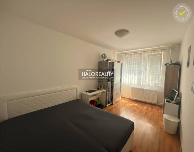 Predaj, trojizbový byt Levice, Rybníky V - Spálňa v 3-izbovom byte s posteľou, podlahou s dreveným dekorom a úložnými priestormi.