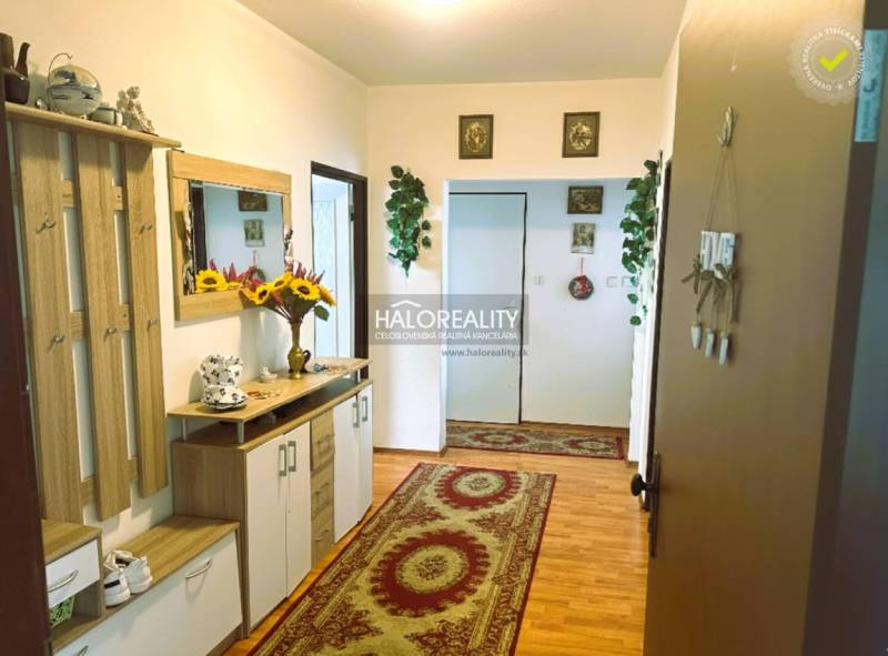 Predaj, trojizbový byt Levice, Rybníky V - Chodba v 3-izbovom byte s podlahou s dreveným dekorom a kvetinovou výzdobou.