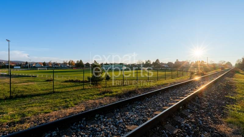 Stavebný pozemok na RD /dvojdom, pri lese za traťou, 1170m2, všetky IS - Železničná trať pri západe slnka v Lozorne na Borovicovej, obklopená zelenými pozemkami na bývanie.
