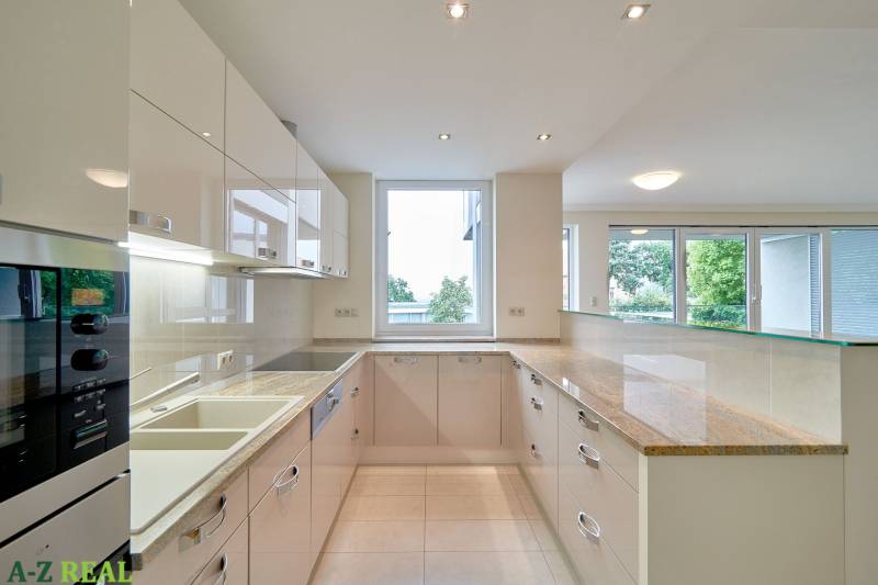 Prenájom exluzívneho 3 izbového apartmánu v Diplomat Parku. - Kuchyňa v 3-izbovom byte s veľkým oknom, bielymi skrinkami a lesklou pracovnou doskou.