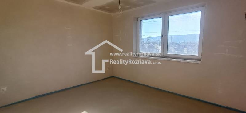 PREDAJ/ Kompletne zrekonštruovaný rodinný dom v Rožňave - Izba v rodinnom dome s omietnutými stenami a veľkým oknom.
