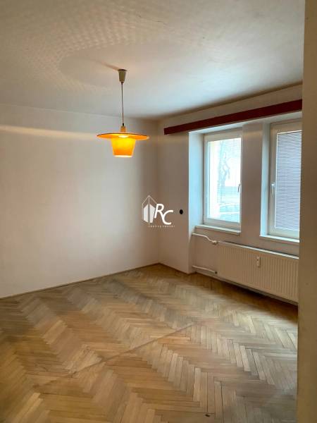 REZERVOVANÉ - Veľký 2-izbový byt s loggiou v centre Martina - Izba v 2-izbovom byte s podlahou s dreveným dekorom a oknom so žalúziami.