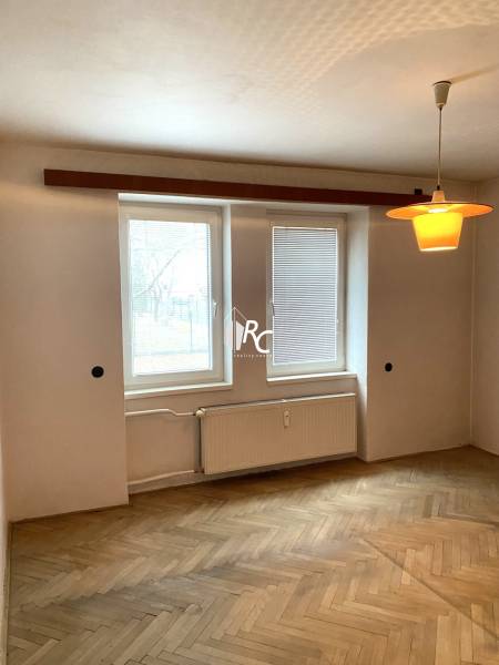 REZERVOVANÉ - Veľký 2-izbový byt s loggiou v centre Martina - Izba so svetlou podlahou s dreveným dekorom, radiátorom a osvetlením v 2-izbovom byte.