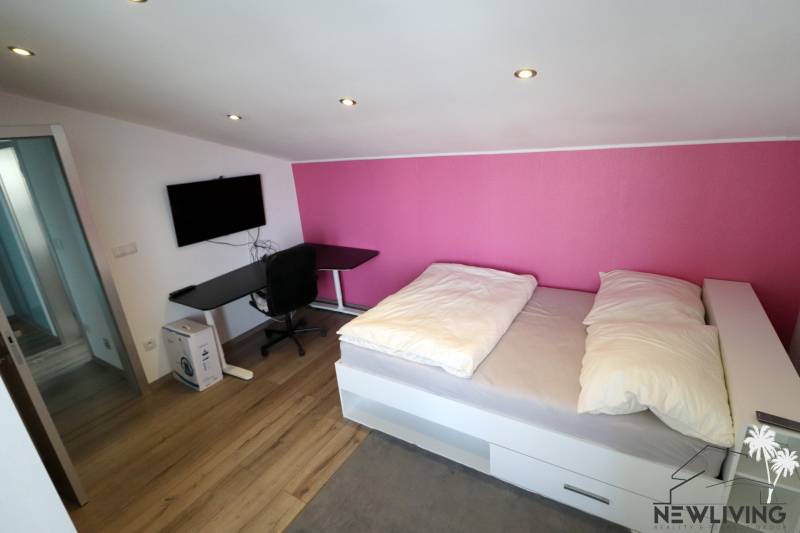 NADŠTANDARDNÝ 5 izbový dom Jánošíkova / Piešťany - Izba v rodinnom dome s podlahou s dreveným dekorom, posteľou a čiernym stolom.