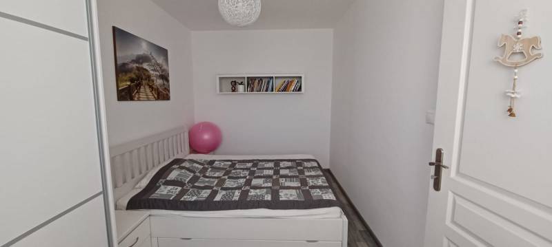 Na predaj 3izbový byt Tranovského , Dúbravka - Spálňa s posteľou, obrazom, knihami a podlahou s dreveným dekorom v 3-izbovom byte.