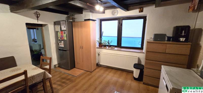 Na predaj 2 izbový rodinný dom, Dolné Orešany! - Kuchyňa v rodinnom dome s podlahou s dreveným dekorom, stolom a chladničkou.