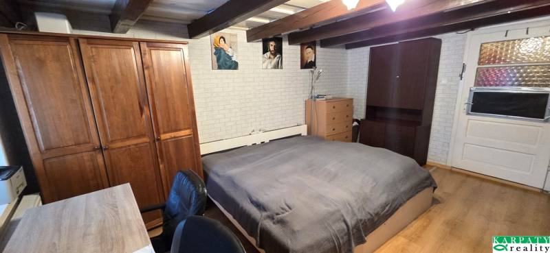 Na predaj 2 izbový rodinný dom, Dolné Orešany! - Spálňa v rodinnom dome s dreveným trámovým stropom, nábytkom a dekoratívnymi obrazmi.
