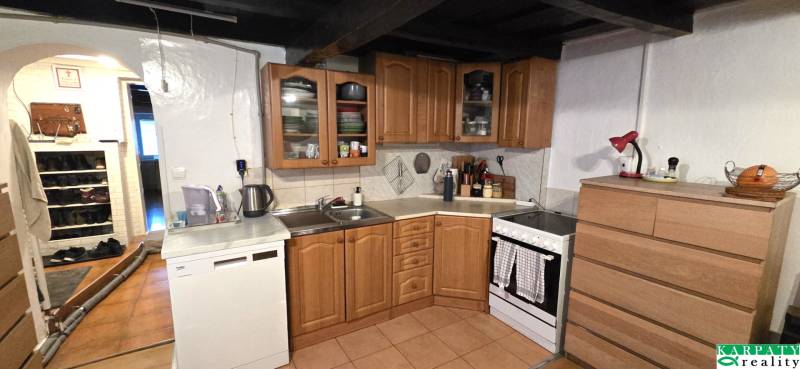 Na predaj 2 izbový rodinný dom, Dolné Orešany! - Kuchyňa v rodinnom dome s drevenými skrinkami, spotrebičmi a bielou stenou.