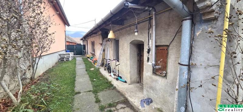 Na predaj 2 izbový rodinný dom, Dolné Orešany! - Exteriér rodinného domu v Dolných Orešanoch s chodníkom, detskými hračkami a zeleňou.